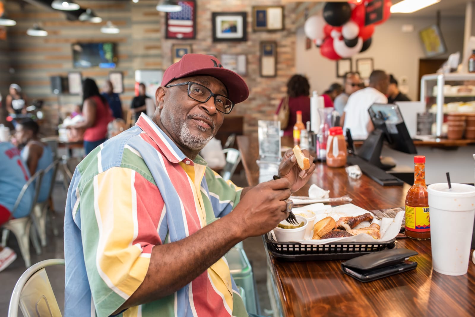 A smiling guest eating a barbecue plate at the counter
