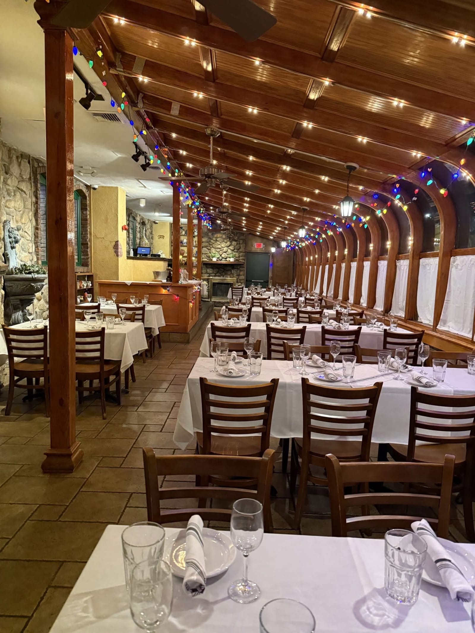 The arched glass sunroom at night, tables set under strings of lights