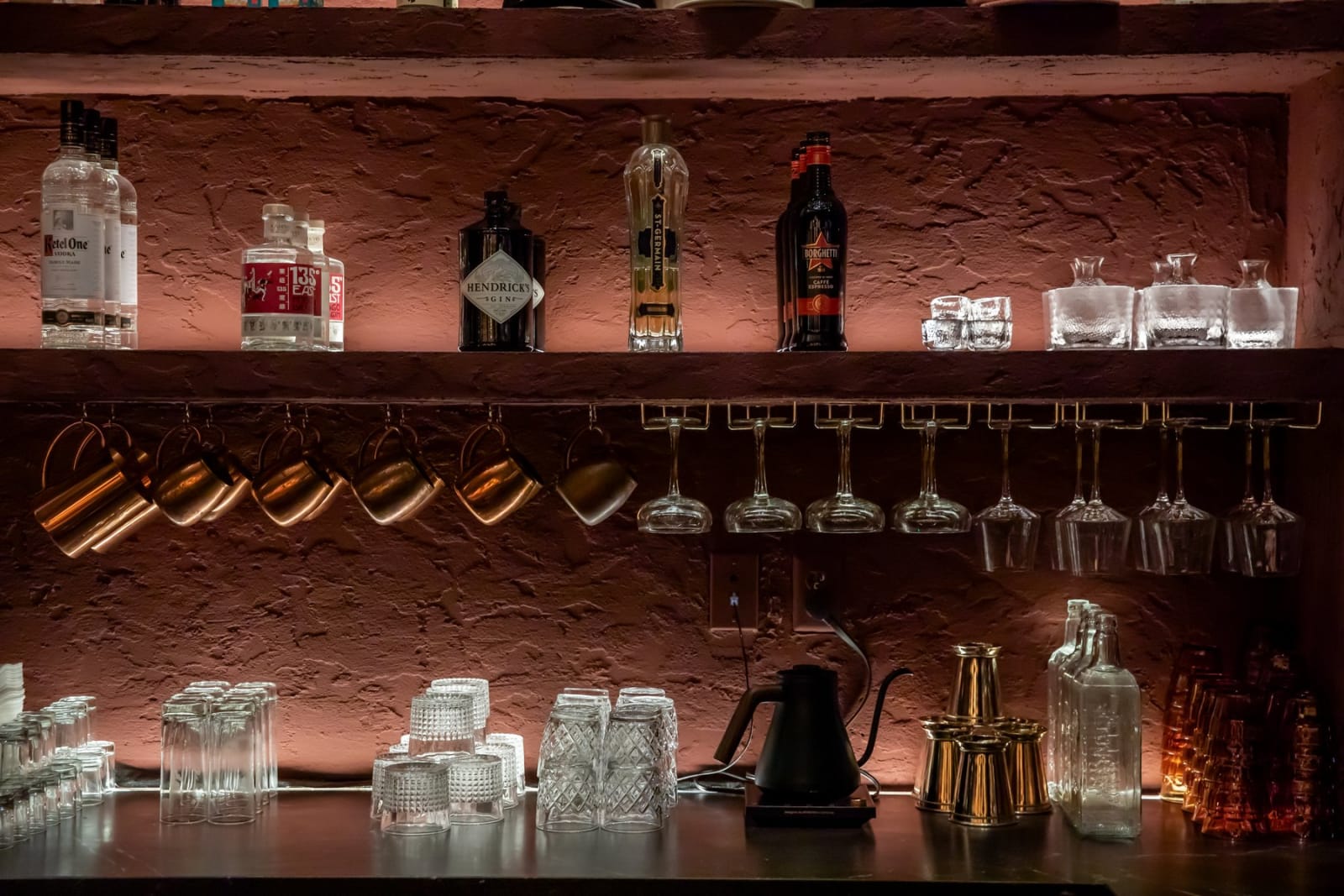 The back bar at Sushi Row: Japanese whiskey and sake bottles, upturned glassware and brass on a terracotta wall