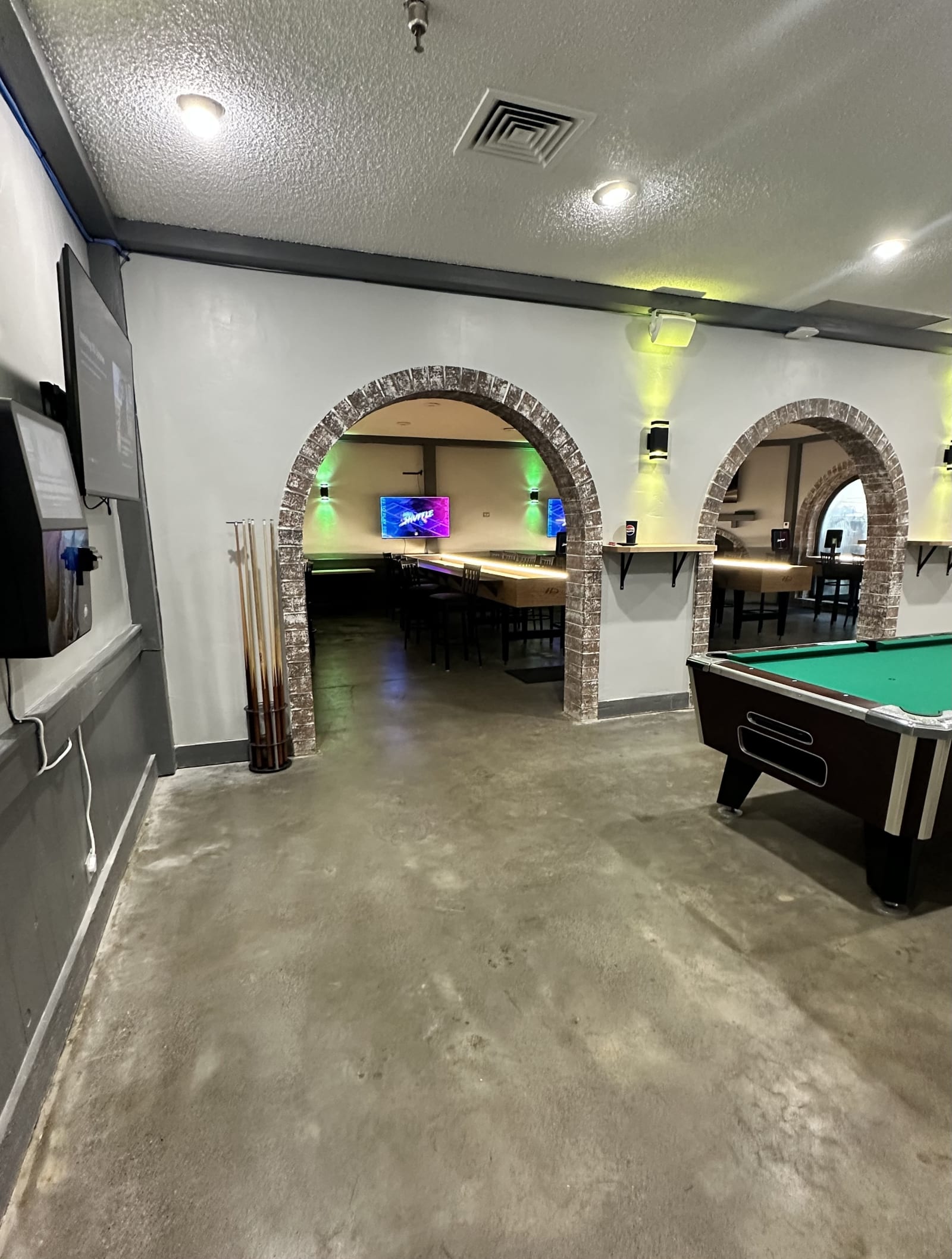 Stone arches framing a pool table and the shuffleboard room beyond