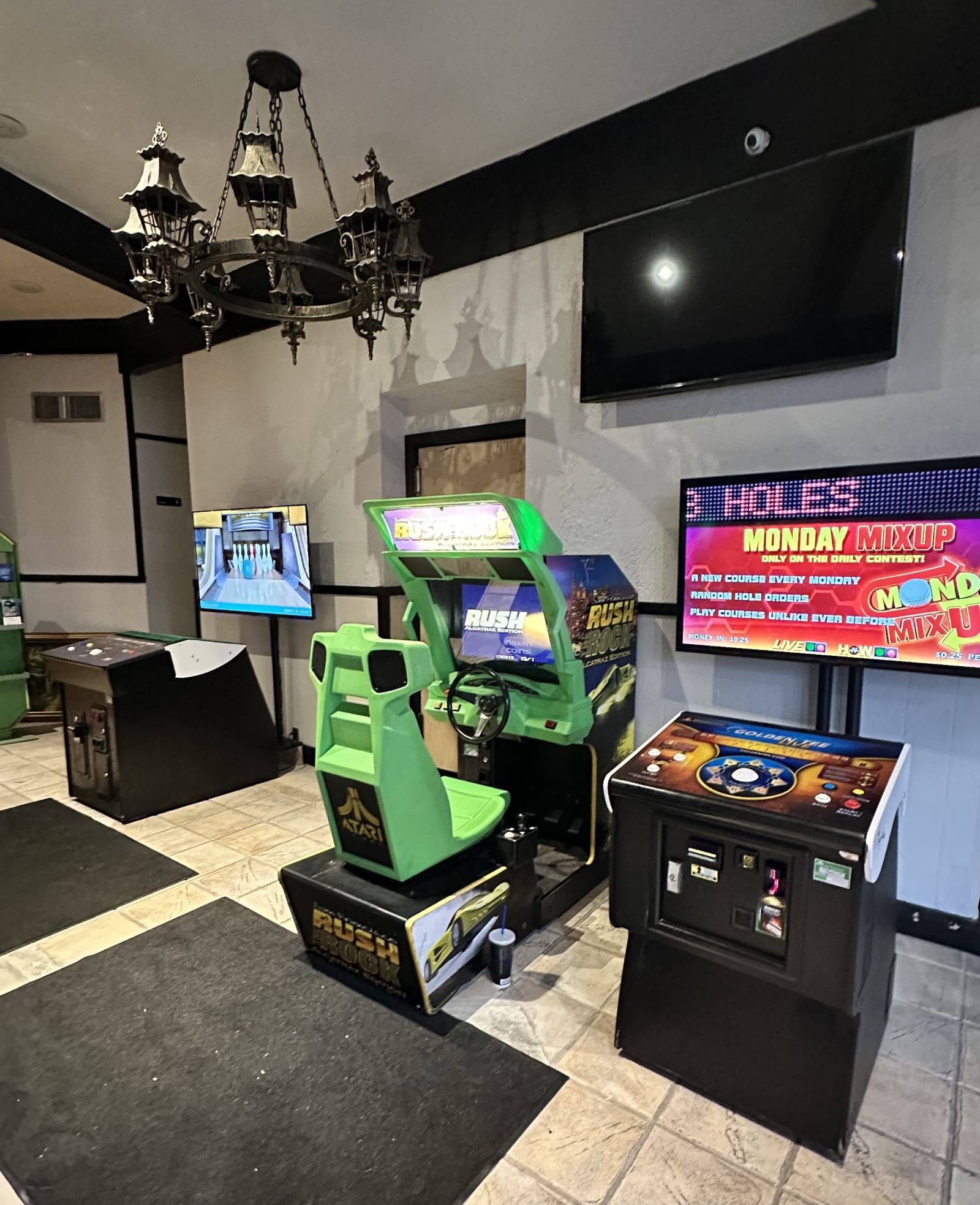 Arcade cabinets under a wrought-iron chandelier at The Drawbridge