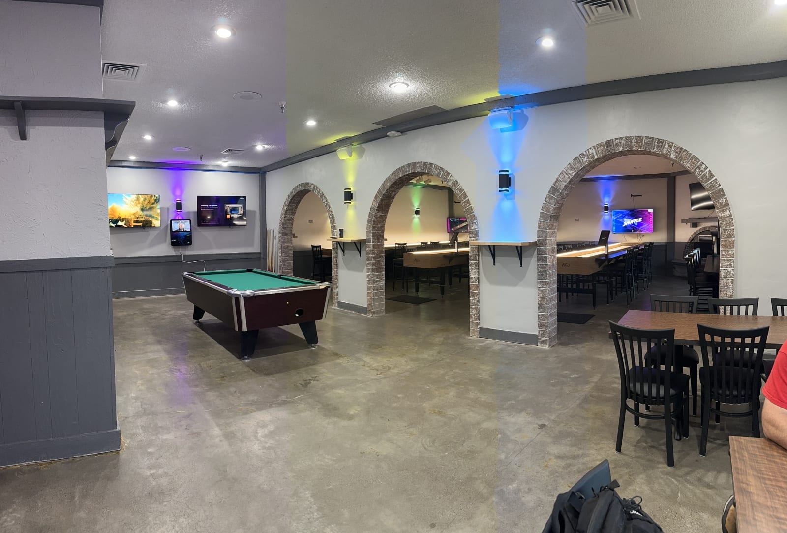 A pool table and dining tables set between three stone arches