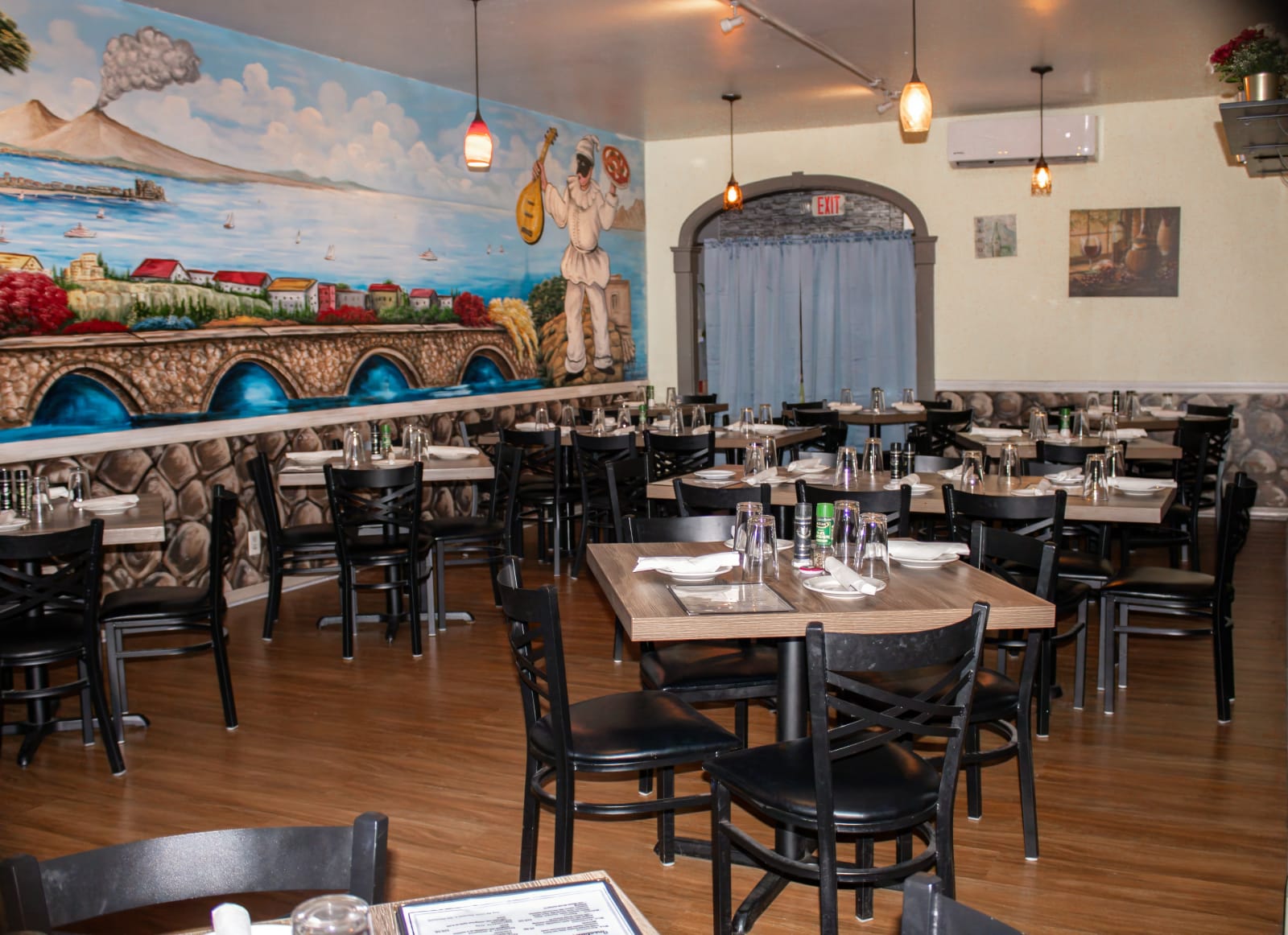 The dining room with its painted Italian coast mural and set tables