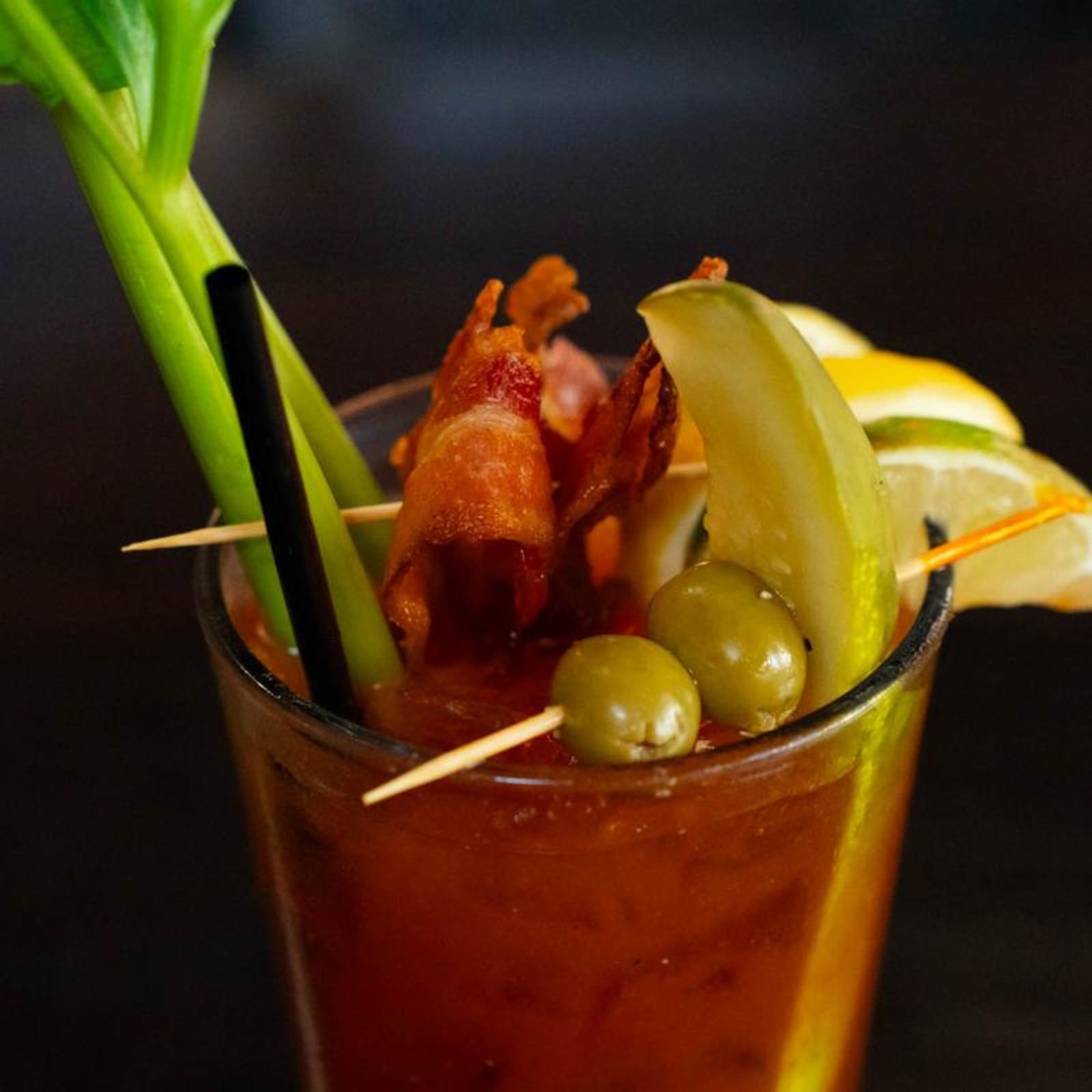 A Bloody Mary garnished with bacon, a pickle spear and olives