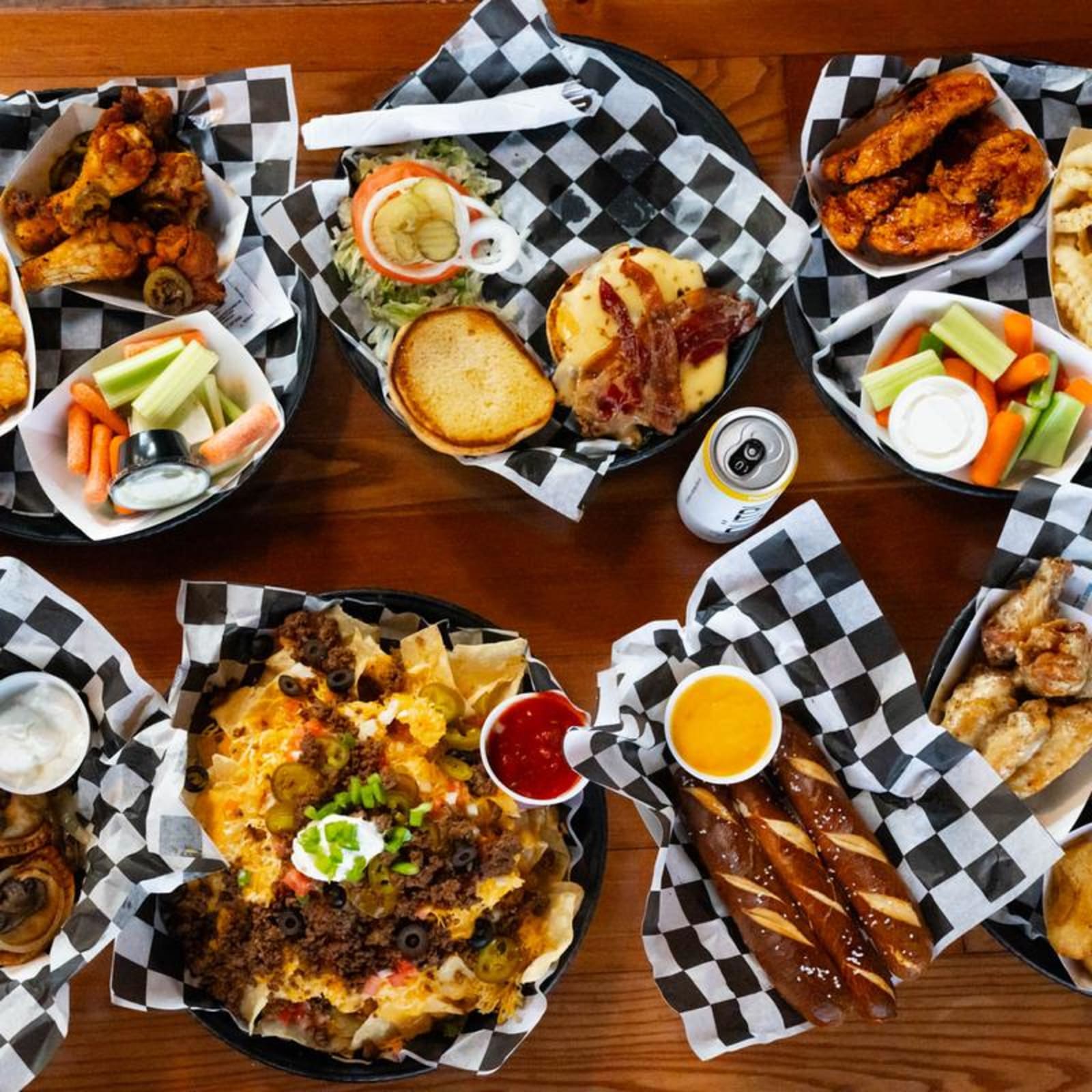 Wings, nachos and pretzels spread across the table in checkered baskets