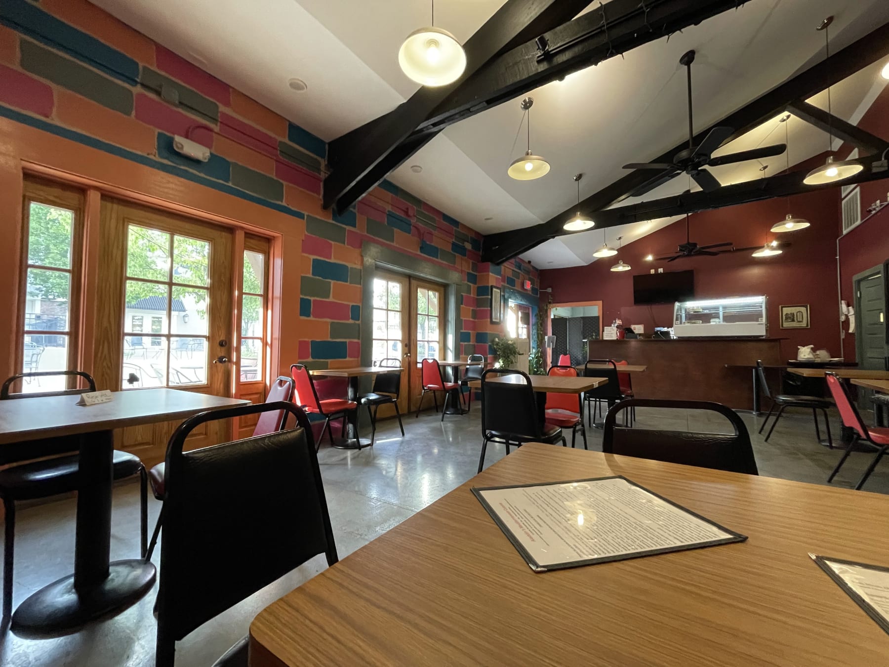 Petra's dining room in New Albany: painted brick walls, wood tables and a wall-sized photo mural of the rock-cut facade at Petra