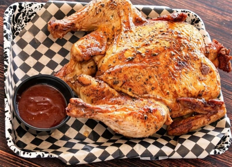 Whole smoked barbecue chicken on checkered deli paper