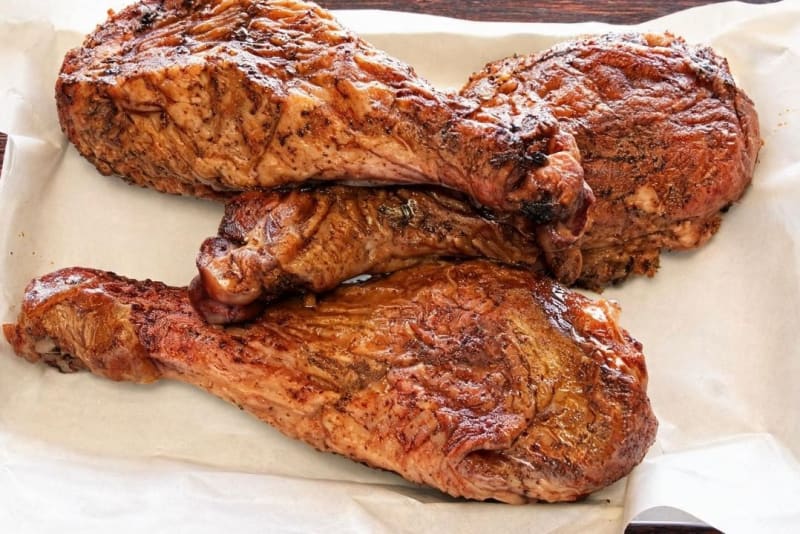 Two smoked turkey legs with deep mahogany skin