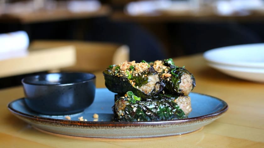 Grilled betel-leaf rolls with toasted sesame on blue ceramic