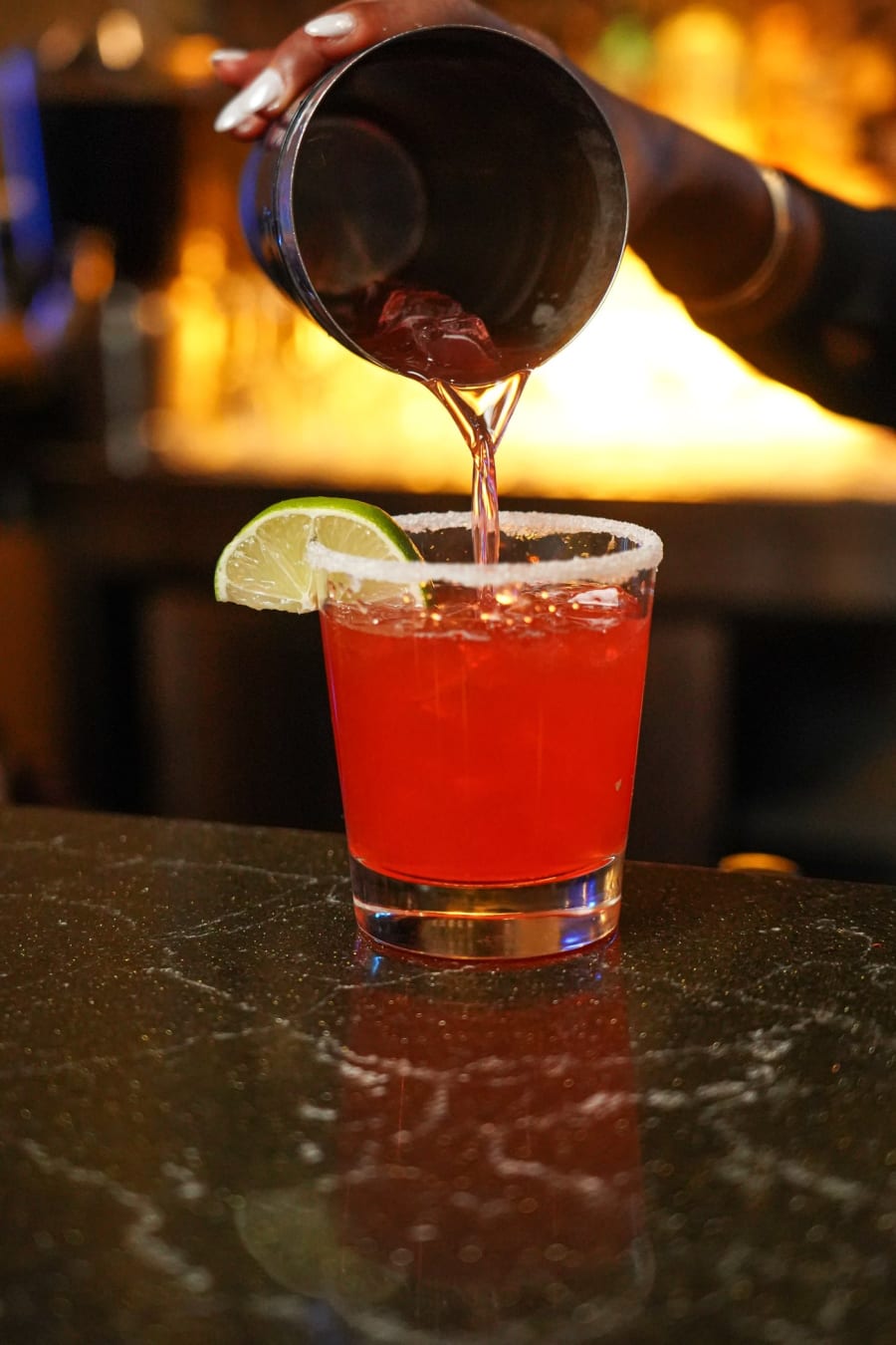 A bartender pouring a red cocktail at the Chocolat bar