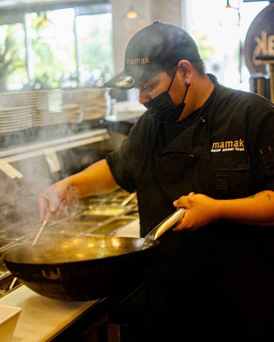 A Mamak cook firing a wok over open flame