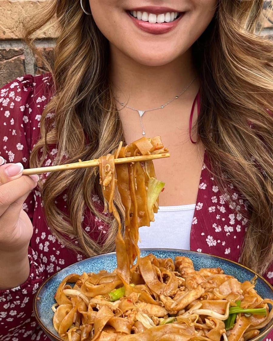 A lift of wide flat rice noodles from a bowl of char kway teow