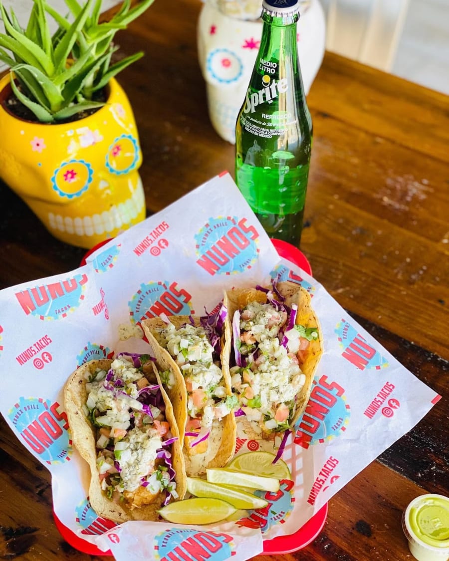 Two Nuno's tacos in a basket on branded paper
