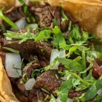 Steak taco with cilantro and onion in a crisp shell