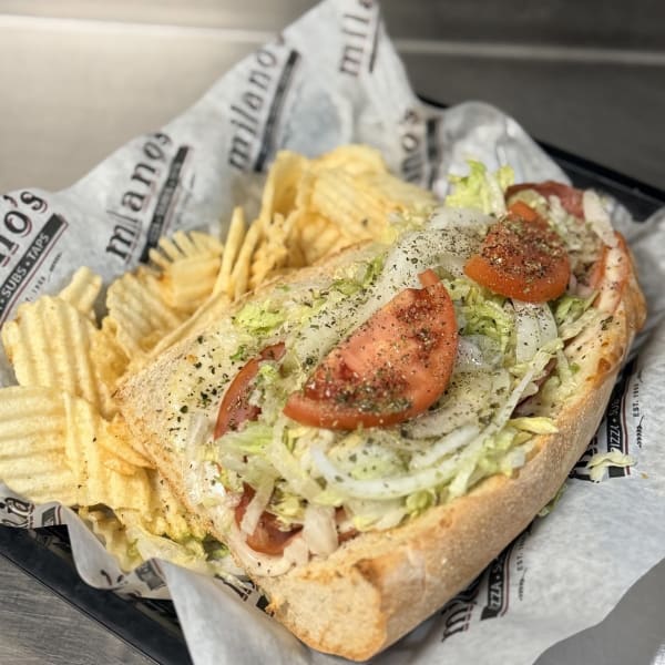 Italian sub loaded with lettuce, tomato and onion, served with chips