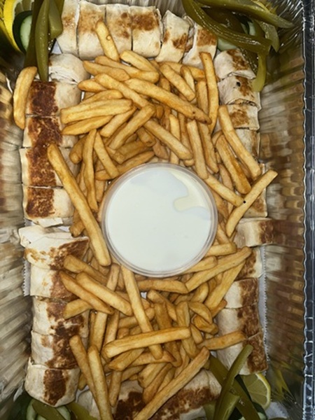 Chicken shawarma wraps sliced on a catering tray with fries and garlic sauce at Petra