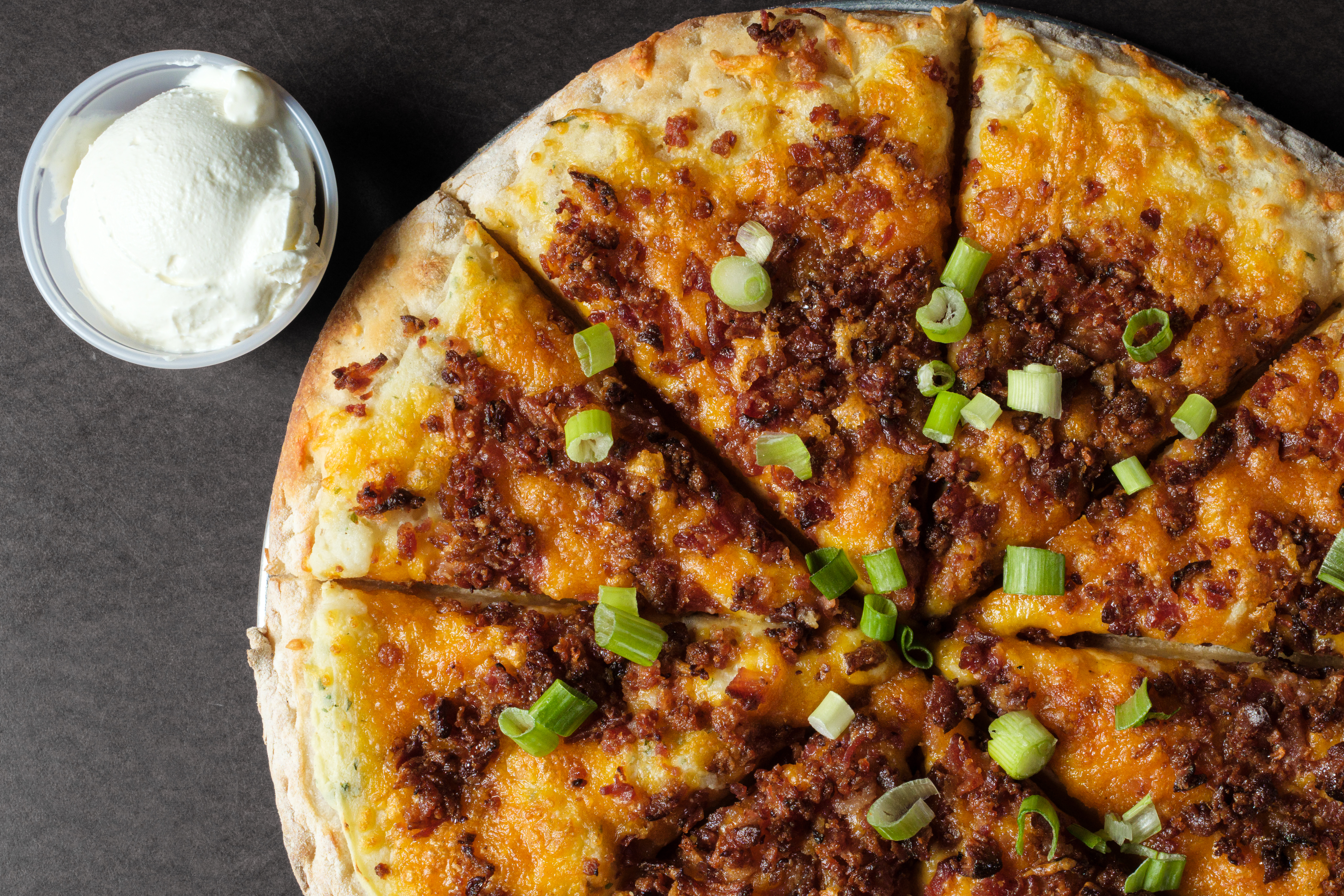 Chicken pizza with ranch drizzle on a wooden board with fresh toppings
