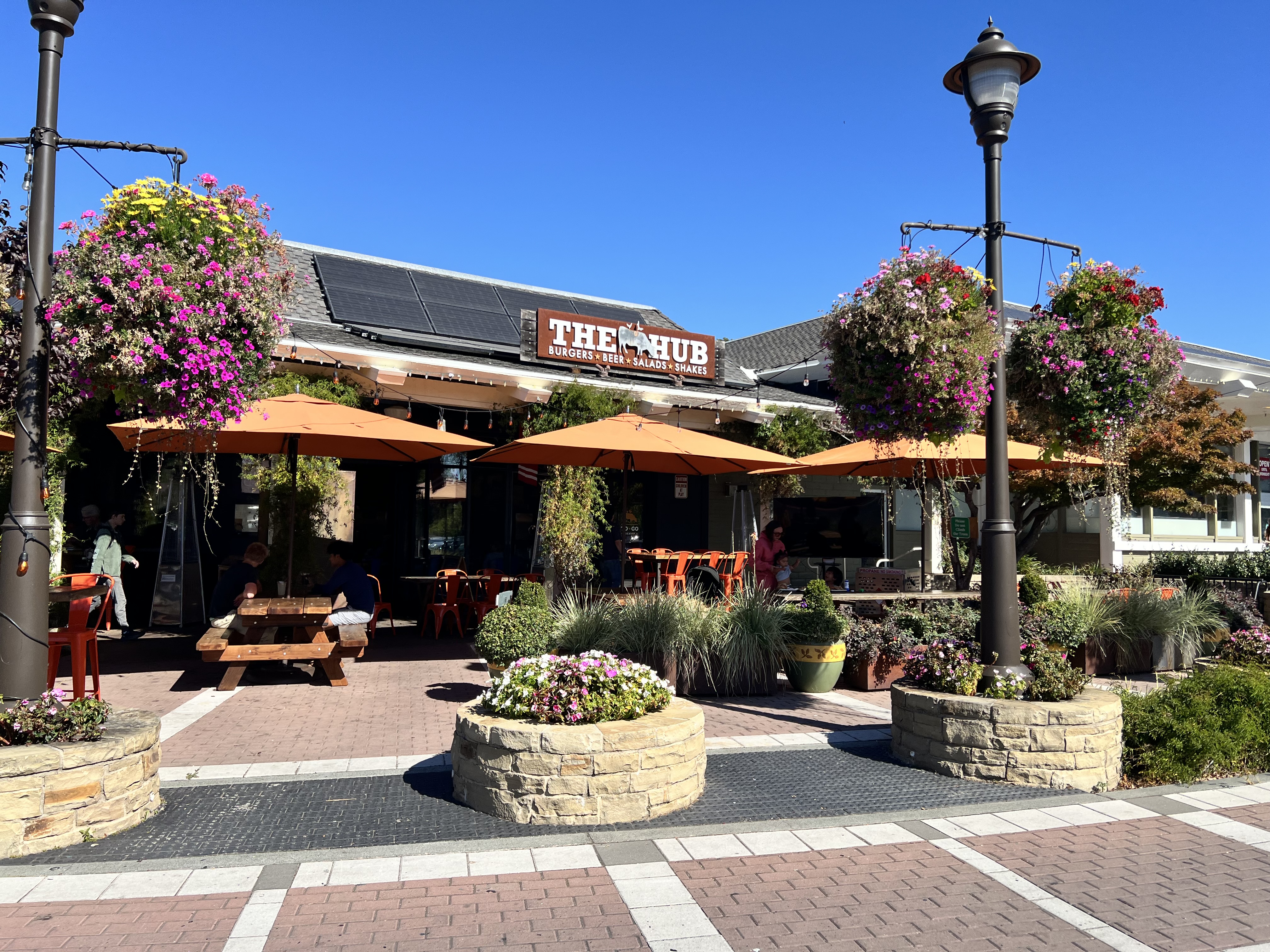 The Hub's outdoor patio at Red Hill Shopping Center, with an orange umbrella and string lights