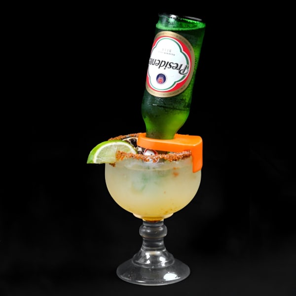 A Presidente beer bottle inverted into a margarita glass with a chili salt rim