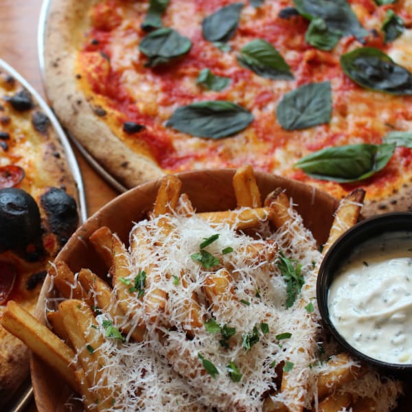 Parmesan-topped fries with garlic aioli beside a margherita pizza