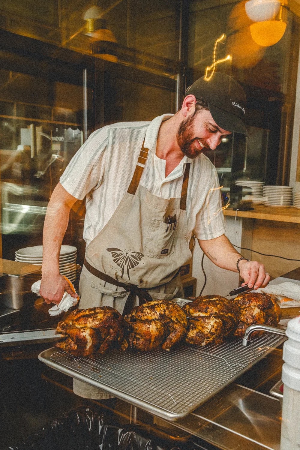 Hand dipping a falafel beside a platter of spiced roast chicken, herbs and sauces
