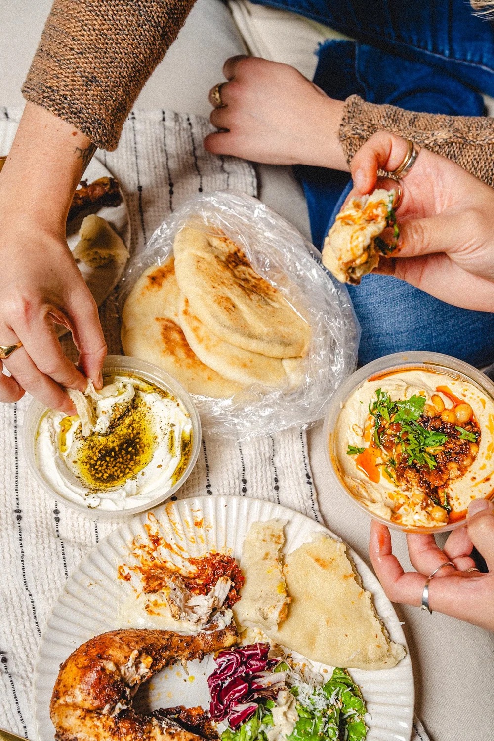Overhead spread of hummus, falafel, pita, chicken and dipping sauces