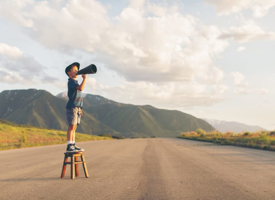 Kid with megaphone on a stool in an open ground