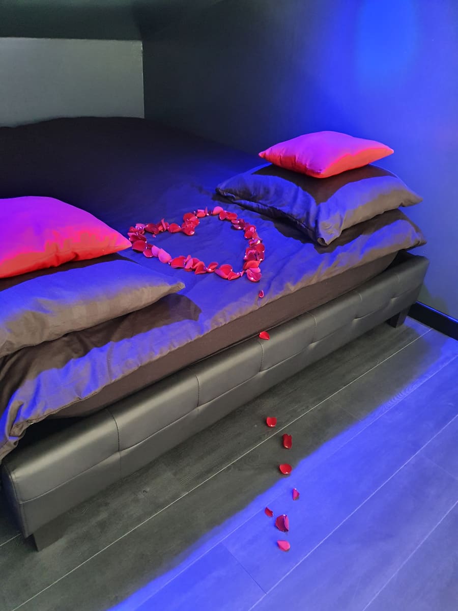 Pétales de roses naturelles disposées en forme de coeur sur le lit