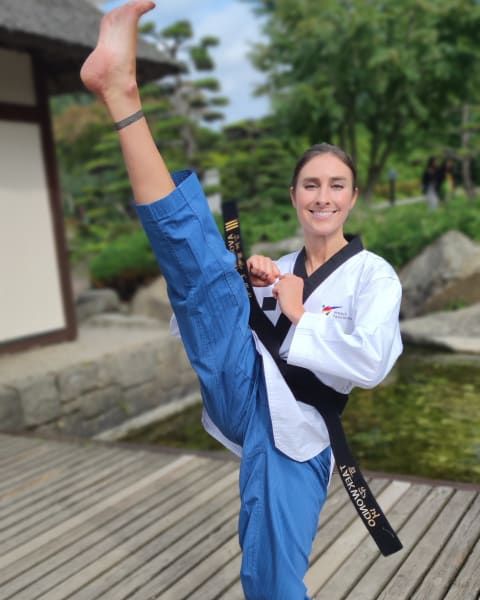 Palina Glebova im Dobok mit hohem Kick auf einem Holzsteg