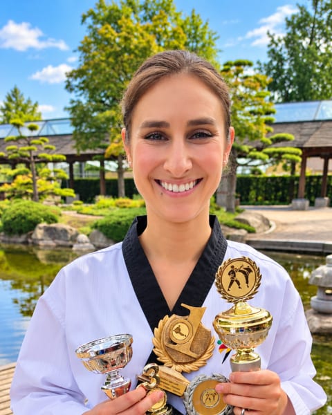 Palina Glebova im Dobok mit mehreren Pokalen im Arm