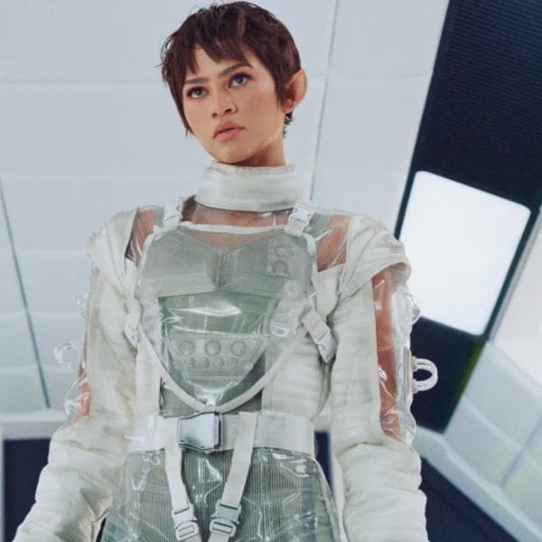 A character in a futuristic outfit stands in a sleek, well-lit environment.