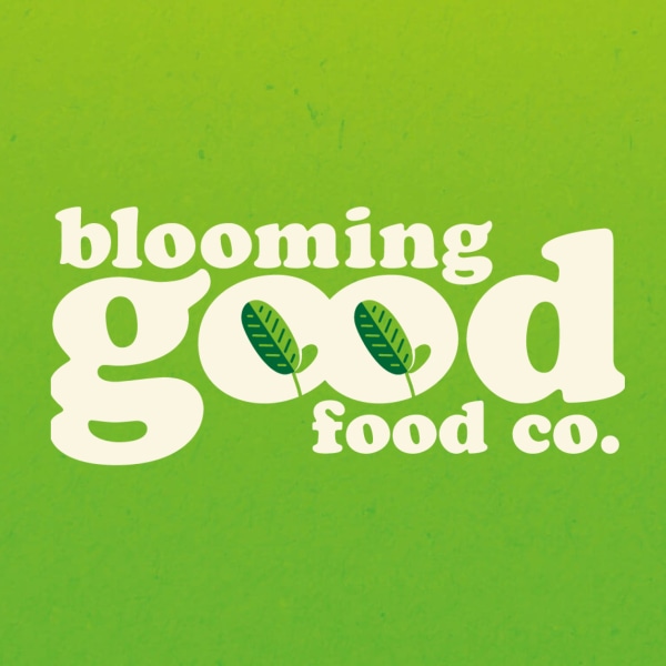 Logo of "blooming good food co." with stylised white text and leaf motif on a vibrant green background, flanked by illustrated vegetables.