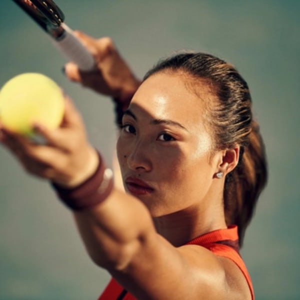 A focused athlete prepares to hit a tennis ball with a racquet.