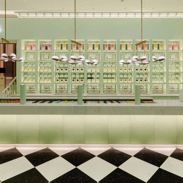 A chic storefront with green decor, display shelves, and a black-and-white checkered floor.