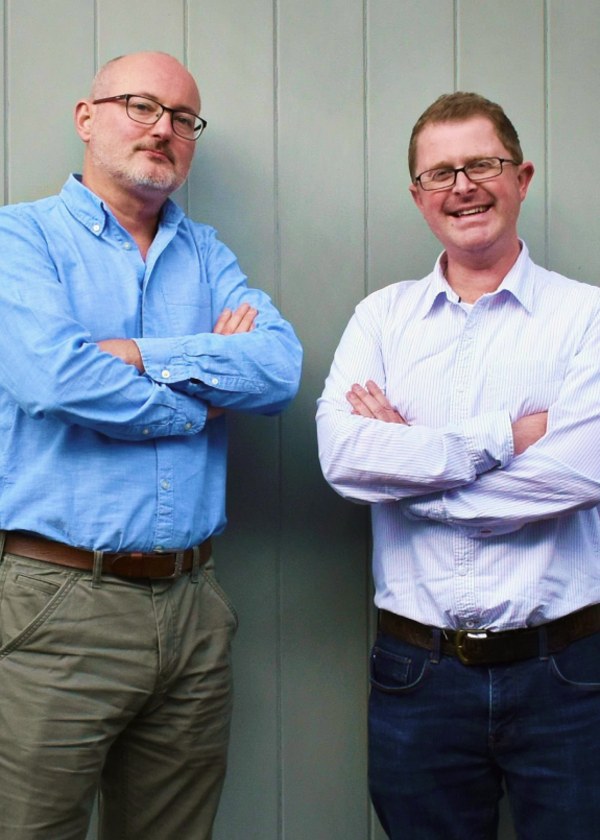 Scott (CTO) and Michael (CEO) standing together in front of a grey wall.