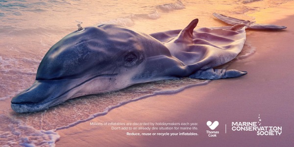 An inflatable dolphin washed up on a beach, promoting marine conservation awareness.