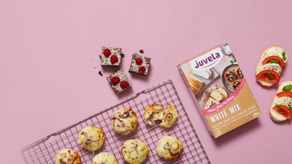 Baked goods on a pink background with a gluten-free mix box and wire rack.