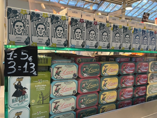 A display of canned fish products with price signs in a market setting.