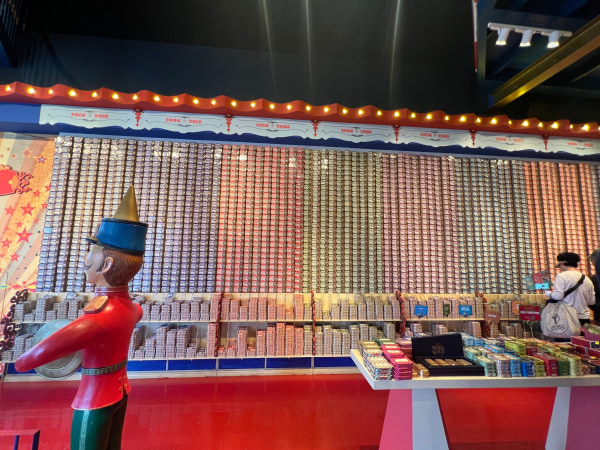 A colorful wall of stacked cans with a toy soldier figure in front.