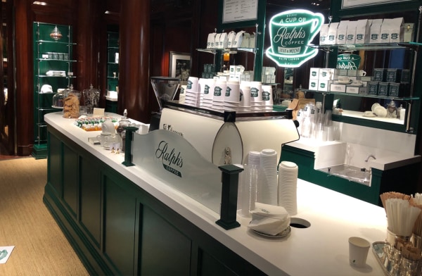 A coffee counter featuring Ralph's Coffee branding, snacks, and green decor elements.