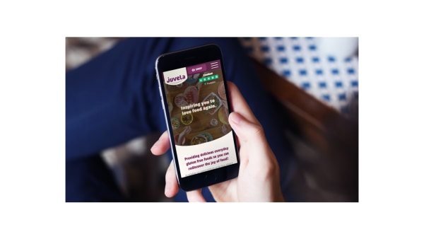 Person holding phone with Juvela website loaded