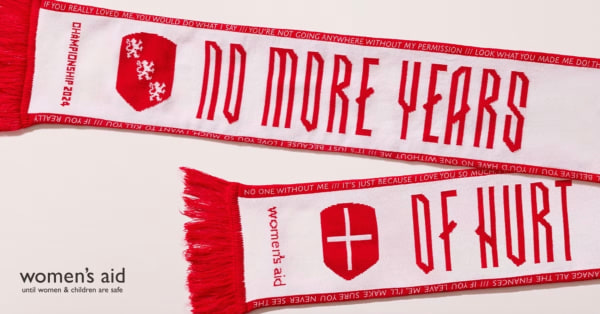 White scarf with red text "NO MORE YEARS OF HURT" and Women's Aid logo, with phrases on domestic abuse awareness.