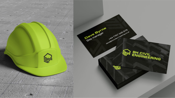 A bright yellow hard hat next to business cards for BH Civil Engineering.