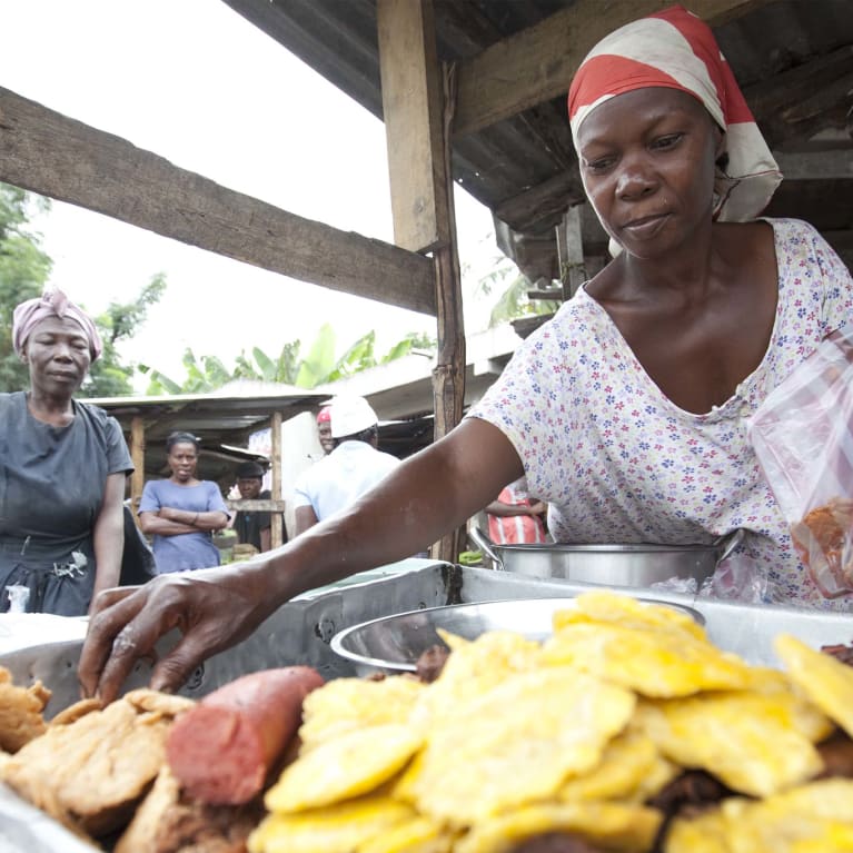 A business woman sells hot snacks at her market stall in Haiti.