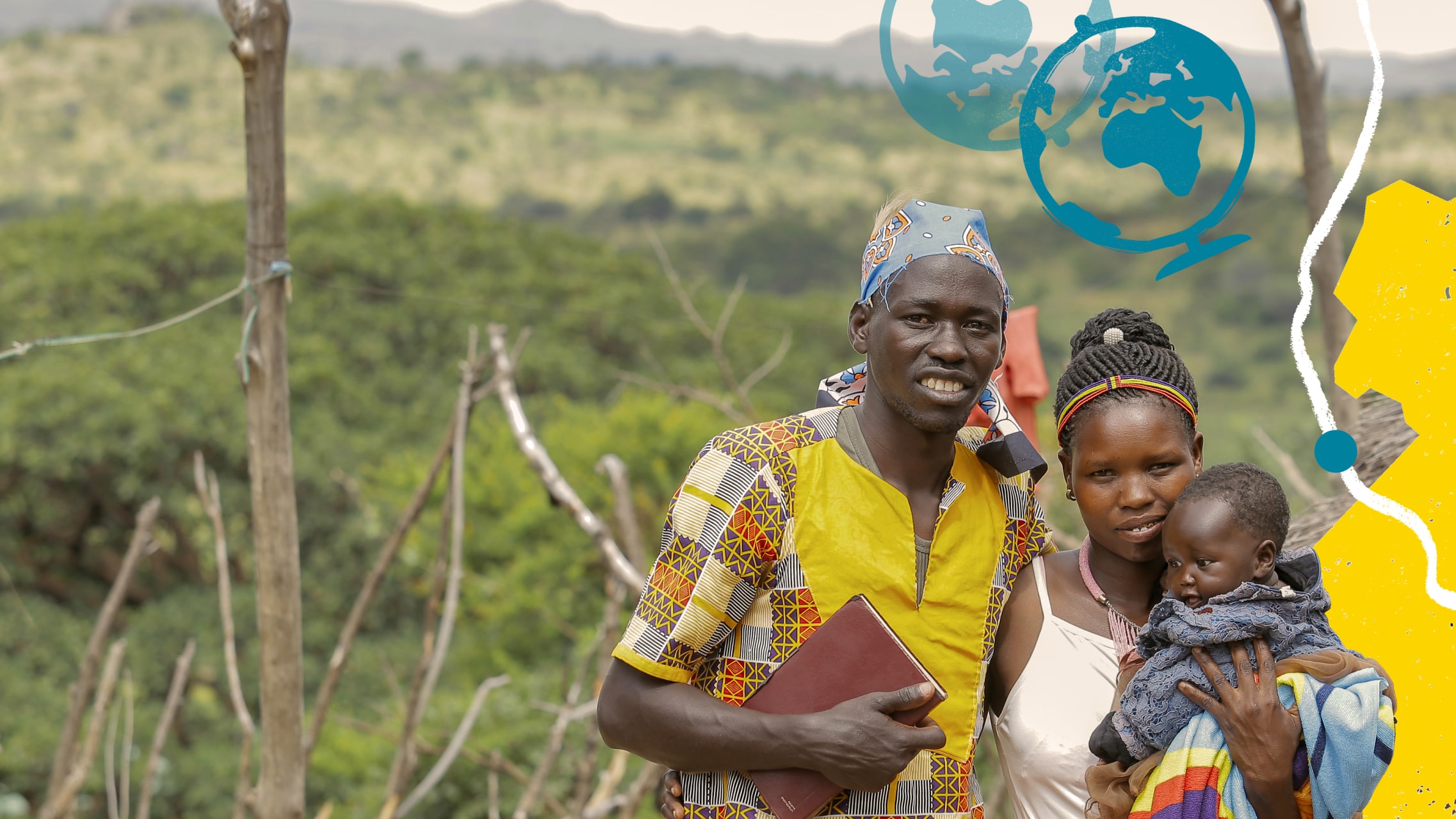 A man puts his arm around a woman, who is holding a child in her arm. The man holds a bible with his other arm. In the background, out of focus is a green and hilly landscape.  