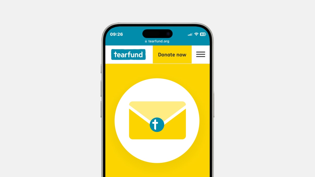Tearfund website on a smartphone, showing an envelope icon with a cross on a yellow background.