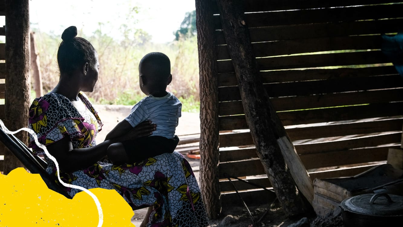 A woman holds a child on her lap looking out of an open doorway