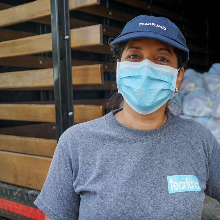 A woman in Tearfund clothes working while wearing a face mask