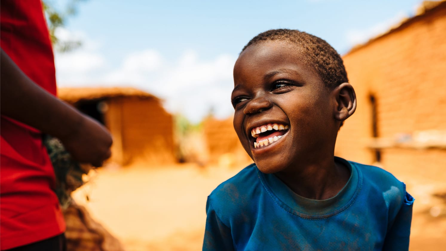 A young boy smiles, looking off to the side. The background is out of focus.