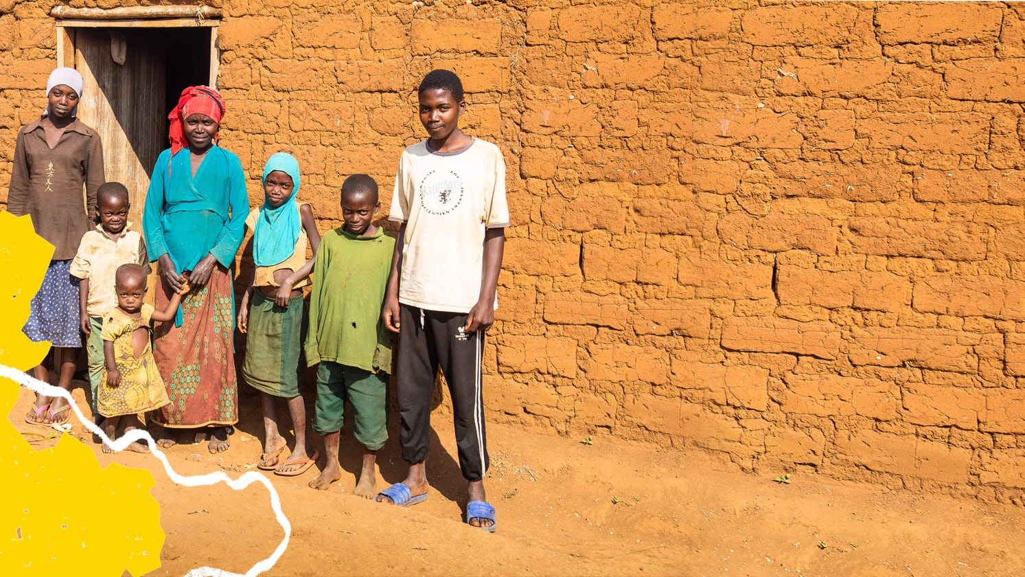 Two adults and five children of varying ages stand outside a building